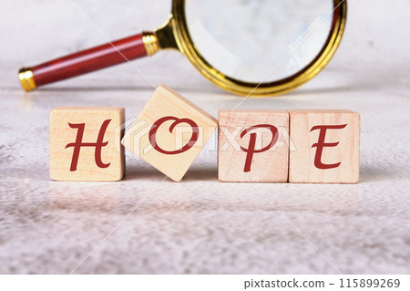 hope word - word abstract in wooden letter cubes Positivity, faith and optimism concept. HOPE assembled from wooden cubes with a magnifying glass in the background without focus 115899269