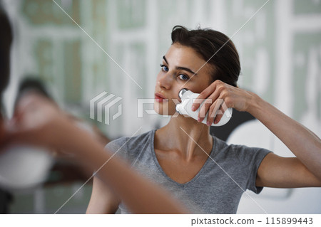 Facial skin care. A woman is doing a face massage using a massager that passes micro current. 115899443