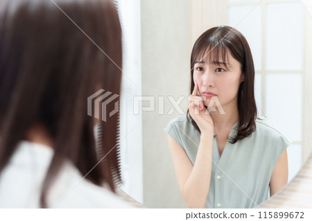 Woman looking in the mirror in the makeup room, skin trouble Woman looking in the mirror in the makeup room, skin trouble 115899672