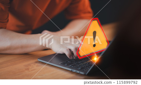 A caution warning sign alerts the user while using a computer laptop, emphasizing the importance of cyber security in detecting viruses, protecting personal data, and maintaining network security. 115899792
