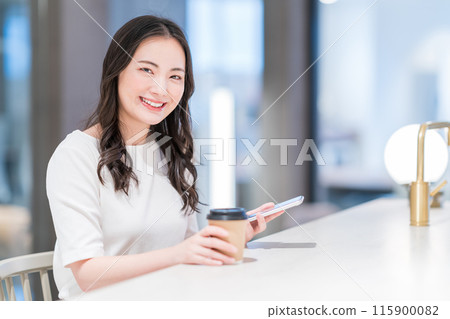A young woman using her smartphone in a cafe. Photo courtesy of WEEK Shibadaimon (Sun Frontier Real Estate) 115900082