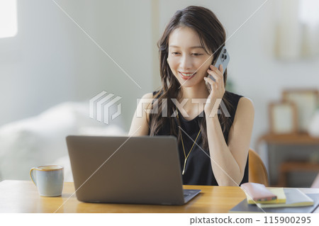 一位年輕女子在客廳在家工作 115900295