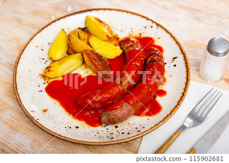 Sausages with potato slices in tomato sauce 115902681