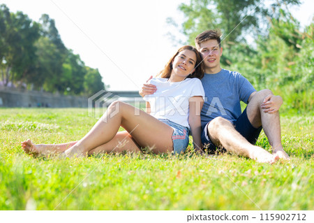 Happy romantic couple sitting on grass in day 115902712