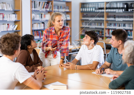Classmates have fun chatting and telling each other in school library Classmates have fun chatting and telling each other in school library 115902788