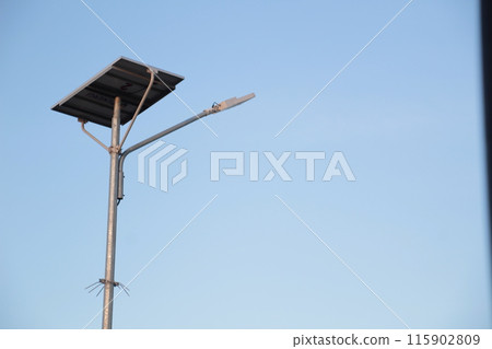 a solar-powered street light with a clear blue sky background. 115902809