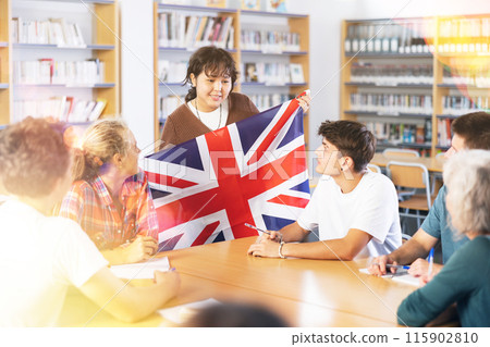 School student girl tells her classmates about the country of Great Britain, holding flag in her hands 115902810
