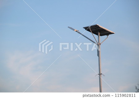 a solar-powered street light with a clear blue sky background. 115902811