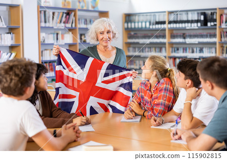 Mature female teacher shows scholchildren the national flag of Great Britain 115902815