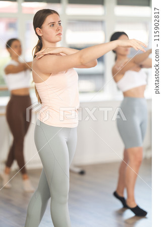 Close-up view of young girl practicing ballet positions standing in row 115902817