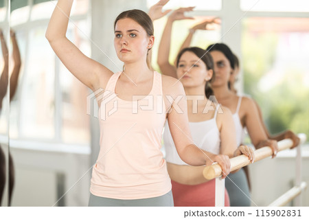 Young female ballet student mastering third position at barre 115902831