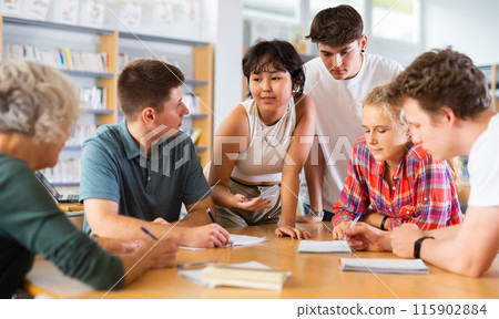 Teenagers in the school library are brainstorming together solving difficult problem Teenagers in the school library are brainstorming together solving difficult problem 115902884