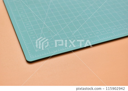 green cutting mat on orange background, object tool for design 115902942