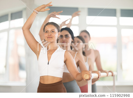Young girl practicing third arm position holding by ballet barre 115902998