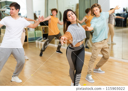 Cheerful hispanic teenage girl learning to dance jive in pair with boy Cheerful hispanic teenage girl learning to dance jive in pair with boy 115903022