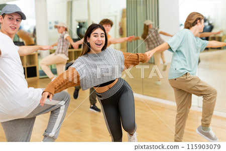 Cheerful hispanic teenage girl learning to dance jive in pair with boy 115903079