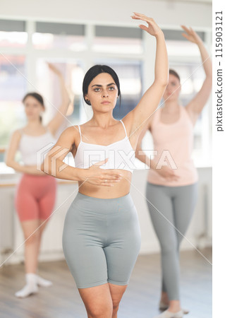 Young girl practicing basic ballet movements at group class 115903121