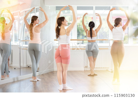 Young girl practicing ballet positions standing in row with others Young girl practicing ballet positions standing in row with others 115903130