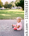 Little girl with chalk sits on the pavement in the park. High quality photo 115903147