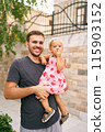 Smiling dad with a little girl in his arms near a stone fence. Portrait. High quality photo 115903152