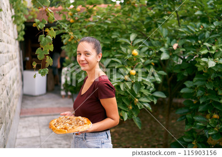 Girl in the garden with onion tarte tatin on a plate. High quality photo Girl in the garden with onion tarte tatin on a plate. High quality photo 115903156