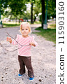 Little girl with a stick in her hands stands in the park. High quality photo 115903160