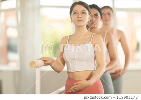 Young girl practicing first arm position holding by ballet barre 115903178