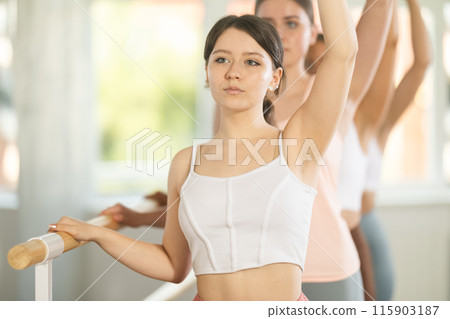 Girl performing third ballet position in group barre fitness workout Girl performing third ballet position in group barre fitness workout 115903187