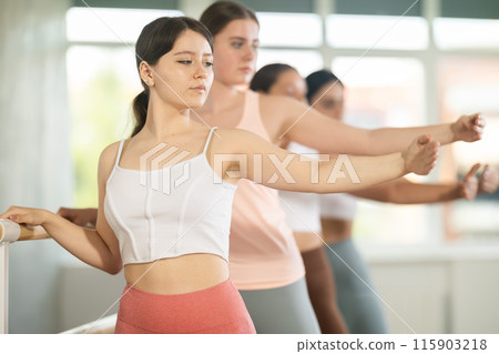 Young girl practicing second arm position holding by ballet barre 115903218