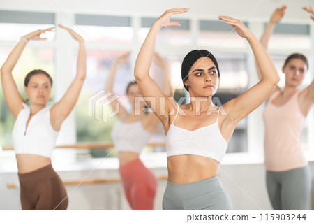 Close-up view of young girl practicing ballet positions standing in row Close-up view of young girl practicing ballet positions standing in row 115903244