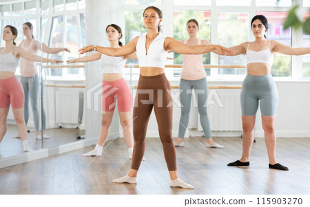 Young girl executing ballet moves during group rehearsal 115903270