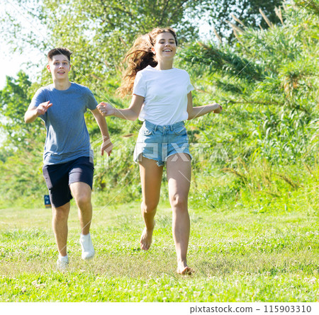 Cheerful teenagers are jogging together in park and having fun 115903310