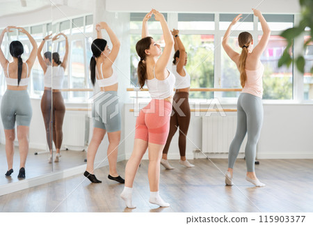 Young girl practicing ballet positions standing in row with others Young girl practicing ballet positions standing in row with others 115903377