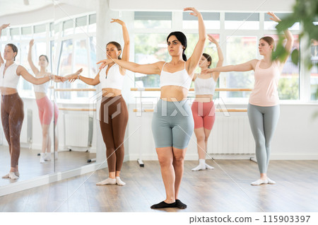 Young girl practicing ballet positions standing in row with others 115903397