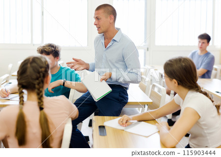 Male teacher working with teen students in classroom at school Male teacher working with teen students in classroom at school 115903444