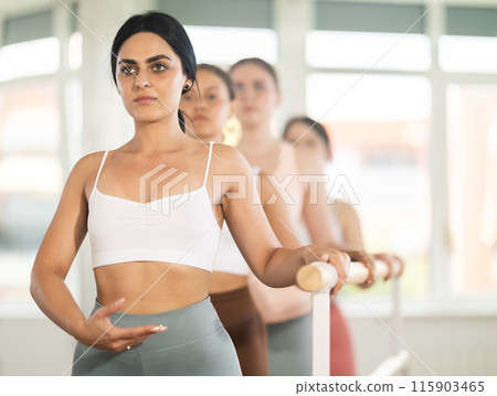 Young girl practicing first arm position holding by ballet barre 115903465