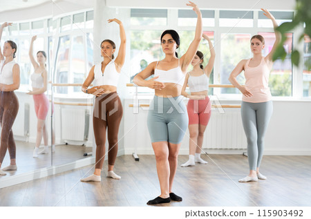 Young girl practicing ballet positions standing in row with others 115903492