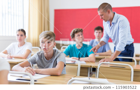 Teenage student writing lectures in workbooks in classroom during lesson Teenage student writing lectures in workbooks in classroom during lesson 115903522