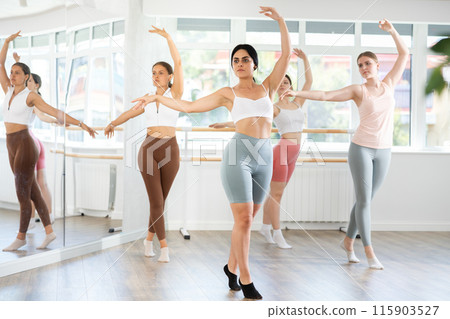 Young girl practicing ballet positions standing in row with others 115903527