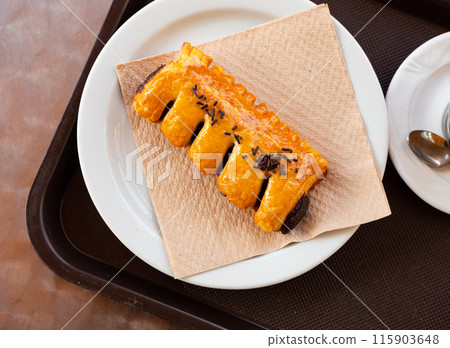 Simple snack is prepared on plate for visitor of cafe - large croissant with chocolate 115903648