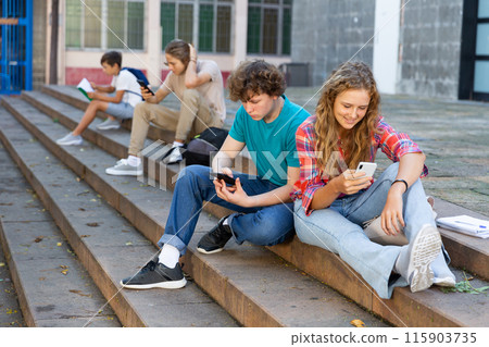 Teenage friends boy and girl holding phones and browsing 115903735