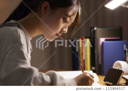 A high school girl studying for an exam in her room A high school girl studying for an exam in her room 115904317