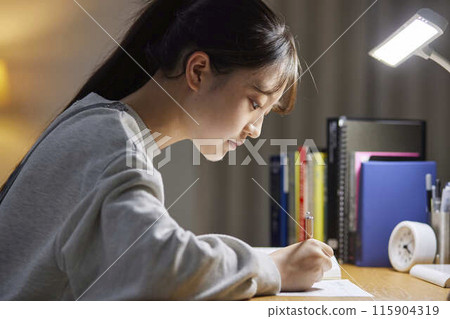 A high school girl studying for an exam in her room 115904319