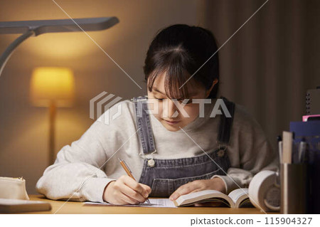 A high school girl studying for an exam in her room 115904327