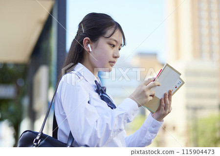 High school girl studying with a reference book High school girl studying with a reference book 115904473