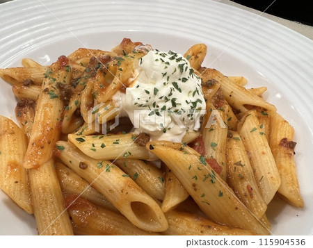 Penne bolognese topped with cheese 115904536