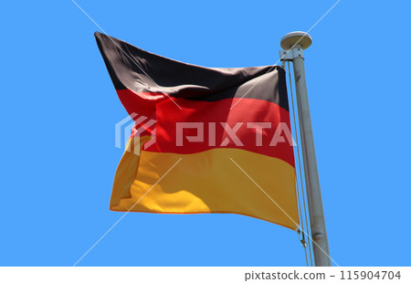 German flag fluttering in the wind under a blue sky 115904704