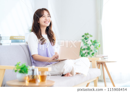 A young woman looking at a computer in the living room 115908454