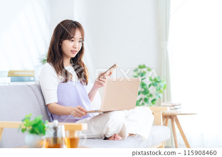 一個年輕女子在客廳裡看電腦 115908460