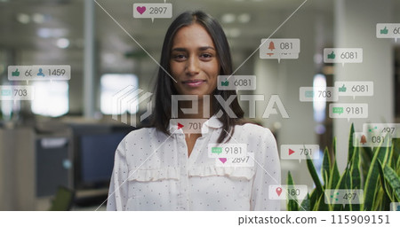 Image of changing numbers, icons in notification bars, smiling biracial woman standing in office 115909151